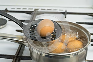 Chicken eggs boil in water. Pan with the product on a gas stove.