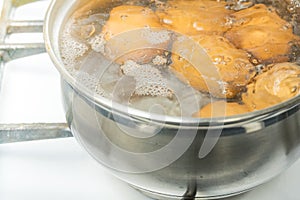 Chicken eggs boil in water. Pan with the product on a gas stove.