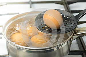 Chicken eggs boil in water. Pan with the product on a gas stove.