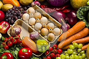 chicken eggs in the center with fresh vegetables on a table