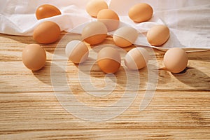 Chicken eggs of different brown and beige shades on a wooden background on white kitchen towel. Easter background