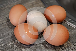 Chicken eggs lying on a wooden tabletop, top view, blurry background