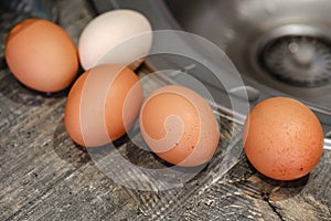 Chicken eggs lying on a wooden tabletop, top view, blurry background