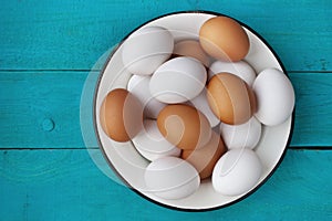 Chicken eggs in a metall dish on the blue boards