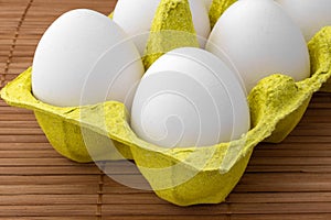 Chicken eggs in a package, isolated on a wooden table, crop