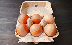 Chicken Eggs in Paper Carton Box Isolated on Black Wooden Table