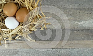 Chicken eggs in straw nest with burlap over wooden background