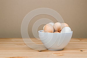 Chicken eggs in a white bowl on the table with copy space
