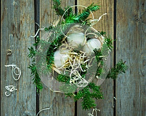 Chicken eggs in a wooden basket with spruce twigs on a wooden tabletop