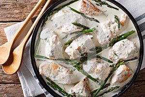 Chicken fillet with asparagus in a creamy sauce close-up on a pl