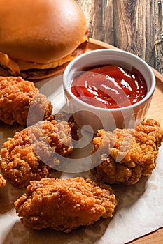 Chicken fried breaded with ketchup on a wooden tray