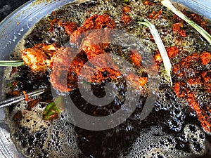 Chicken fried in hot oil in a pan