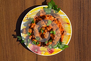 Chicken gizzard stew in plate on wooden table