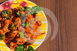 Chicken gizzard stew in plate on wooden table