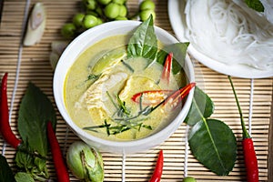 Chicken green curry Thai food on soup bowl with rice noodles ingredient vegetable herbs and spices pepper chili wooden background