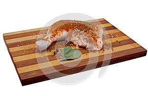 Chicken ham is sprinkled with spices and bay leaf on wooden, bamboo cutting board.