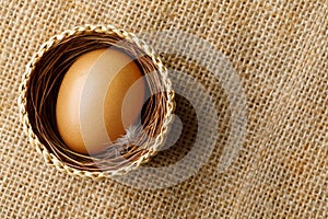 Chicken or hen egg in wicker basket on sackcloth