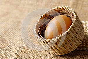 Chicken or hen egg in wicker basket on sackcloth