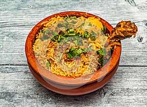 chicken hyderabadi biryani served in claypot isolated on wooden table top view of indian spicy food