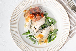 Chicken Kiev with wild garlic, with baked cherry tomatoes And green beans, on white stone  background, top view flat lay