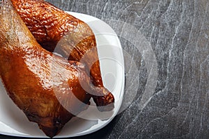Chicken legs cooked on a grill on a white plate on a black background in closeup. Top view from above. Copy space. Natural food