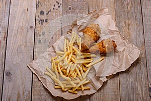 Chicken legs and french frie on wooden background