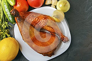 Chicken legs of a poultry, cooked on a grill and organic vegetables on a black wooden background. Top view. Copy space