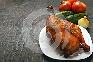 Chicken legs of a poultry, cooked on a grill on a white plate. Fresh organic vegetables on a black background. Copy space