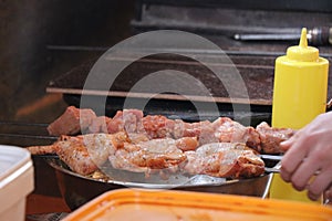 Chicken legs and wings are cooked over a fire in a large stone grill. Delicious food at the campfire.