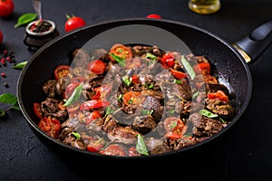 Chicken liver offal with onions and tomatoes in a frying pan