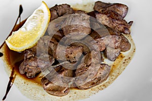 Chicken liver with wine and soy sauce, garnished with slice of lemon. Closeup.