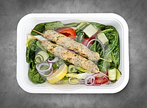 Chicken lula kebab with herbs and vegetables. Healthy food. Takeaway food. Top view, on a gray background