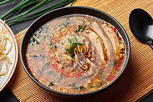 Chicken Manchow Soup in black bowl at dark slate background. Chicken Manchow Soup is indo-chinese cuisine dish