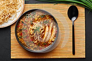 Chicken Manchow Soup in black bowl at dark slate background. Chicken Manchow Soup is indo-chinese cuisine dish