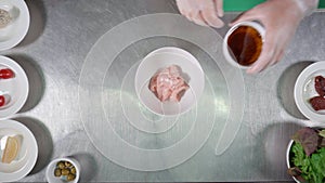 Chicken meal cooking concept. Male hands marinates chicken pieces in bowl with oil and soy sauce on kitchen tables