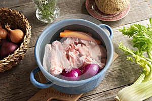 Chicken meat, onions and carrots in a pot - ingredients for bone broth