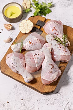 Chicken meat. Raw fresh chicken drumsticks with spices on a woden cutting board on a stone countertop