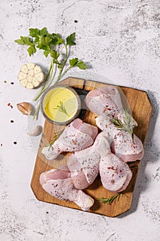 Chicken meat. Raw fresh chicken drumsticks with spices on a woden cutting board on a stone countertop. Top view flat lay