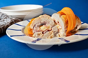 Chicken meat roulade stuffed with cheese and ham, sliced carrot on plate,towel,plates