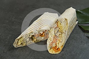 Chicken meat shawarma isolated on dark stone background. Gyros wrapped in lavash bread