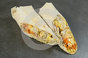 Chicken meat shawarma isolated on dark stone background. Gyros wrapped in lavash bread