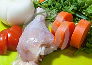 Chicken meat, tomatoes, parsley and carrot were chopped on plastic cutting board