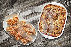 Chicken Meat with Vegetable Stew and Gibanica Cheese Pie Slices in Platters on Old Wooden Garden Table Surface photo