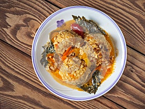 Chicken meatballs with rice and vegetables on a light plate, serving on a wooden tray