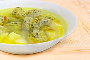 Chicken meatballs soup in white bowl closeup at selective focus