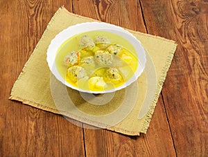 Chicken meatballs soup in white bowl on old rustic table
