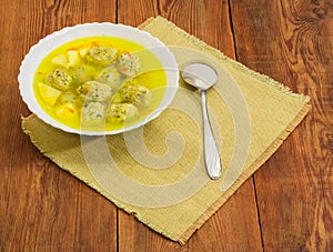 Chicken meatballs soup in white bowl and spoon on napkin