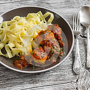 Chicken meatballs in tomato sauce and fettuccine pasta in a brown bowl