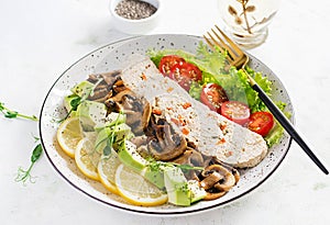 Chicken meatloaf, fried mushrooms with salad fresh tomatoes and avocado.