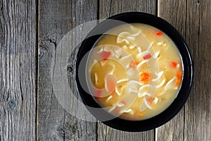 Chicken noodle soup, above view on rustic wood